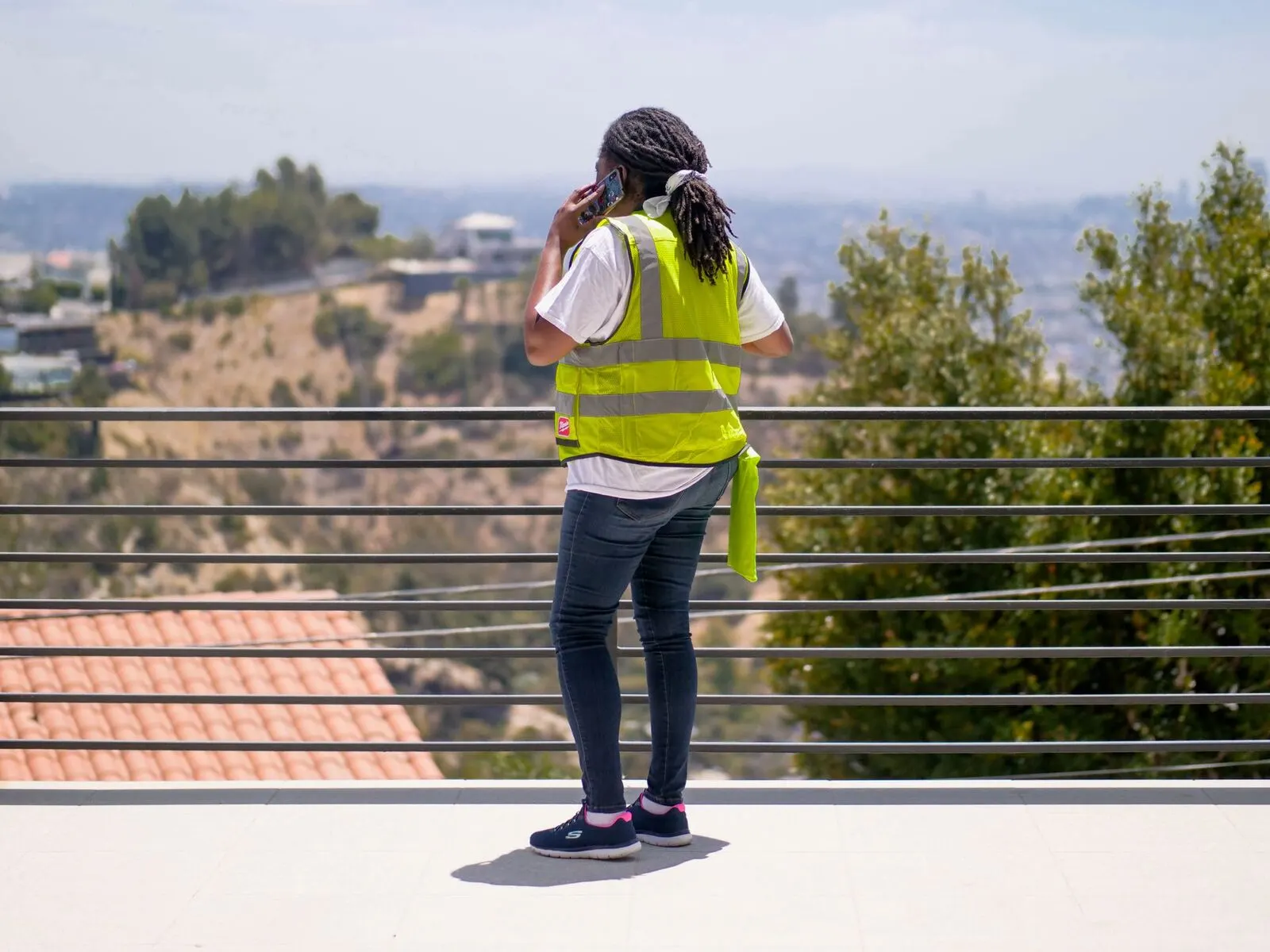 Tradesperson on-site taking a call while wearing PPE and a hi-vis vest