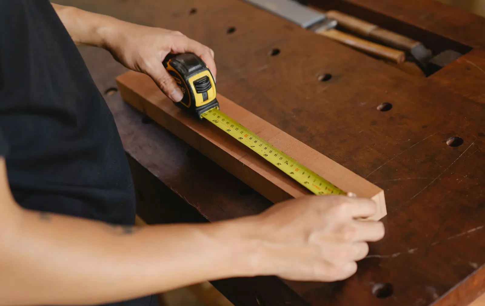 Carpenter measuring wood in a workshop — a West Midlands trades business we support